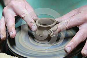 Hands of a potter, creating an earthen jar on pottery wheel.