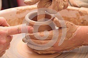 Hands of a potter, creating an earthen jar on pottery wheel.