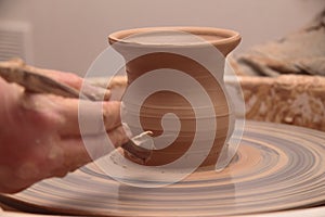 Hands of a potter, creating an earthen jar on pottery wheel.