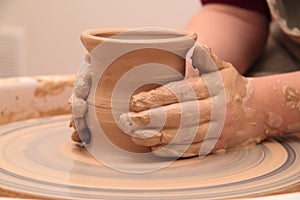 Hands of a potter, creating an earthen jar on pottery wheel.