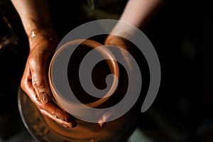 Hands of potter do a clay pot