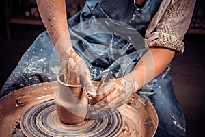 hands of potter do a clay pot