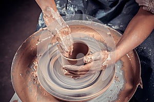 Hands of potter do a clay pot photo