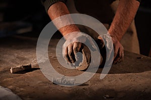 Hands of the potter knead clay.