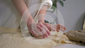 Hands potter kneading clay on worktable for making earthenware at crafting studio