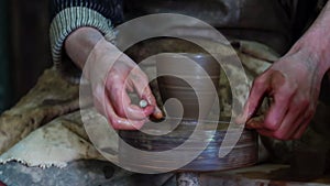 Hands of potter making clay pot on manual potters wheel with foot drive. Handicraft pottery making