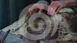 Hands of potter making clay pot on manual potters wheel with foot drive. Handicraft pottery making