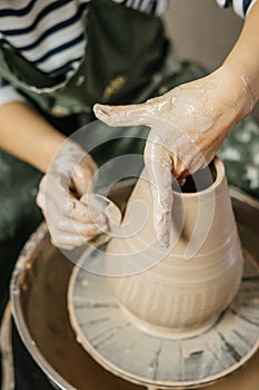 Hands of potter making clay pot on potter`s wheel