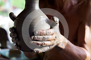 Hands of a potter manufactures clay pot