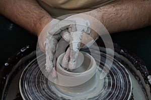 Hands of a potter on a pottery. Pottery workshop in subdued soft light