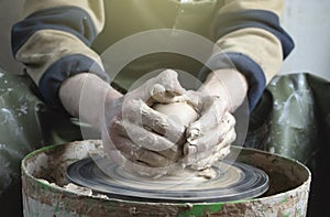 Hands of a potter on a pottery wheel close-up. Old traditional art, handmade, clay and ceramic production. Pottery workshop in