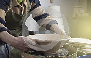 Hands of a potter on a pottery wheel close-up. Old traditional art, handmade, clay and ceramic production. Pottery workshop in