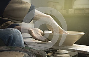 Hands of a potter on a pottery wheel close-up. Old traditional art, handmade, clay and ceramic production. Pottery workshop in