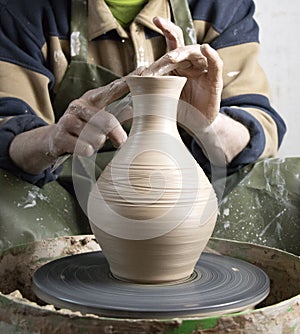 Hands of a potter on a pottery wheel close-up. Old traditional art, handmade, clay and ceramic production. Pottery workshop in