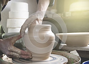 Hands of a potter on a pottery wheel close-up. Old traditional art, handmade, clay and ceramic production. Pottery workshop in