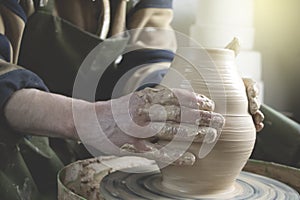 Hands of a potter on a pottery wheel close-up. Old traditional art, handmade, clay and ceramic production. Pottery workshop in