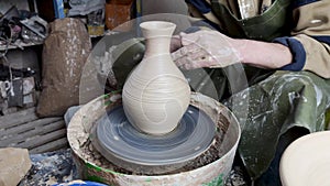 Hands of a potter on a pottery wheel close-up. Old traditional art, handmade, clay and ceramic production. Pottery workshop in