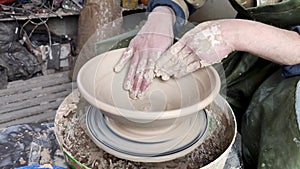 Hands of a potter on a pottery wheel close-up. Old traditional art, handmade, clay and ceramic production. Pottery workshop in