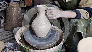 Hands of a potter on a pottery wheel close-up. Old traditional art, handmade, clay and ceramic production. Pottery workshop in