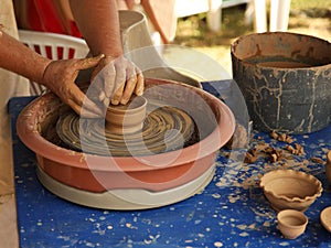 Hands of a potter sculpt clay dishes on a pottery wheel. Folk craft for making dishes. Creation of a ceramic product