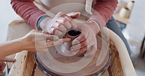 Hands, pottery and clay with a man student learning from a female potter in the studio or ceramic workshop. Art