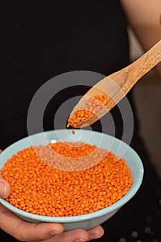Hands Pouring Red Lentils into Bowl. Hands overflowing with vibrant red lentils over a bowl
