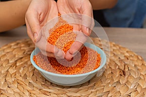 Hands Pouring Red Lentils into Bowl. Hands overflowing with vibrant red lentils over a bowl