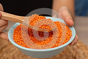 Hands Pouring Red Lentils into Bowl. Hands overflowing with vibrant red lentils over a bowl