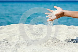 A hands pouring sand near the seashore on weekend nature travel