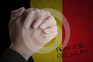 Hands pray for Belgium with Belgian flag