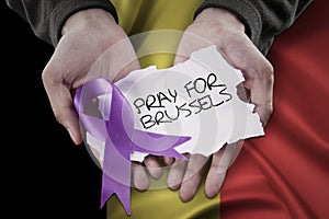 Hands pray for Brussels with ribbon