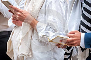 Hands and prayer book close-up. Orthodox hassidic Jews pray in a holiday robe and tallith