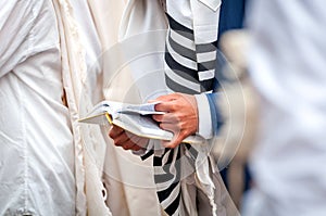 Hands and prayer book close-up. Orthodox hassidic Jews pray in a holiday robe and tallith