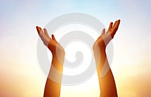 hands praying on blurred sunset sky background