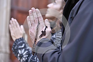 Hands of a praying couple holding prayer beads
