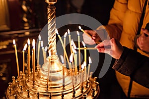 Hands of praying people lighting candles in Christian church. Concept of faith in God. Religious scene. Close-up