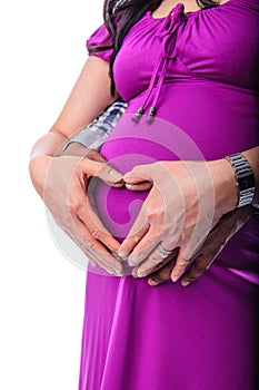 Hands of pregnant couple holding tummy with heart shape hands