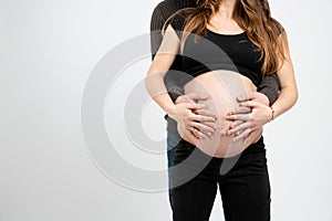 Hands of Pregnant Mother and father standing holding belly, young family concept, isolated over white background