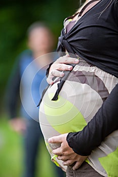 hands of pregnant woman and her female partner in heart shape on her belly