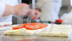 Hands prepare sandwich with tomato mozzarella