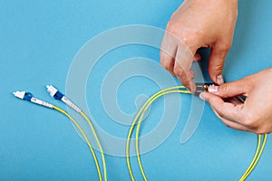 Hands prepare to tune a variable optic attenuator with a screwdriver. Blue background