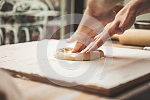 Hands preparing dough basis for pizza