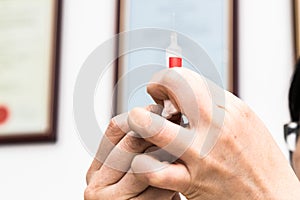 Hands preparing injection syringe against backdrop of medical certificates