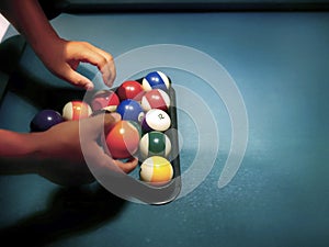 Hands preparing pool balls in triangle rack on the billiard table