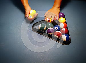 Hands preparing pool balls in triangle rack on the billiard table