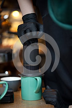 Hands pressing aeropress into cup, closeup of coffee brewing