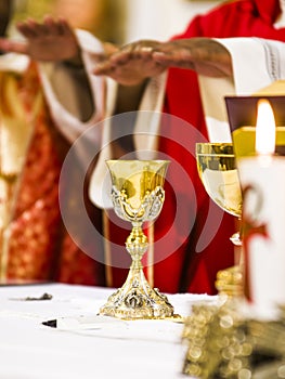 Hands of the priest consecrate wine and bread on the altar of holy mass