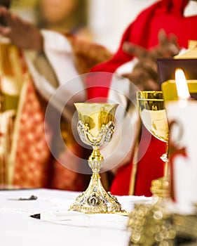 Hands of the priest consecrate wine and bread on the altar of holy mass