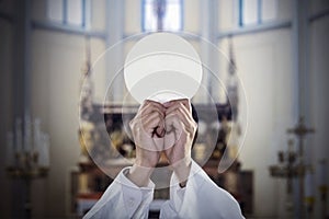 Hands of Priest raise a communion bread in church