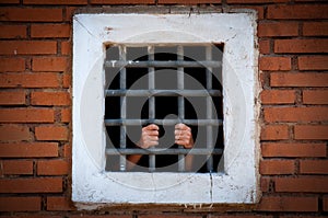 Hands of prisoner behind the bars, color